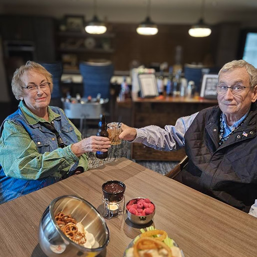 A senior couple at Aura Independent Living share a table filled with appetizers.
