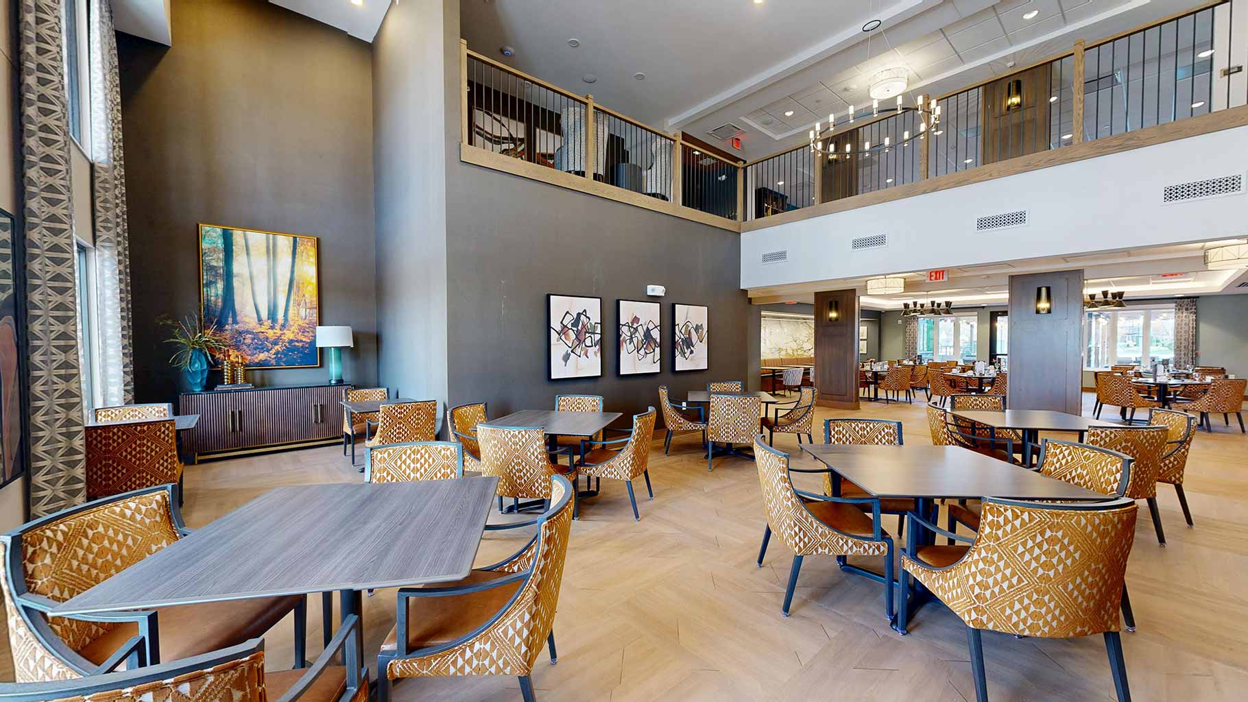 Dining area at Aura Independent Living, showcasing warm, modern design, and second-story seating area views.
