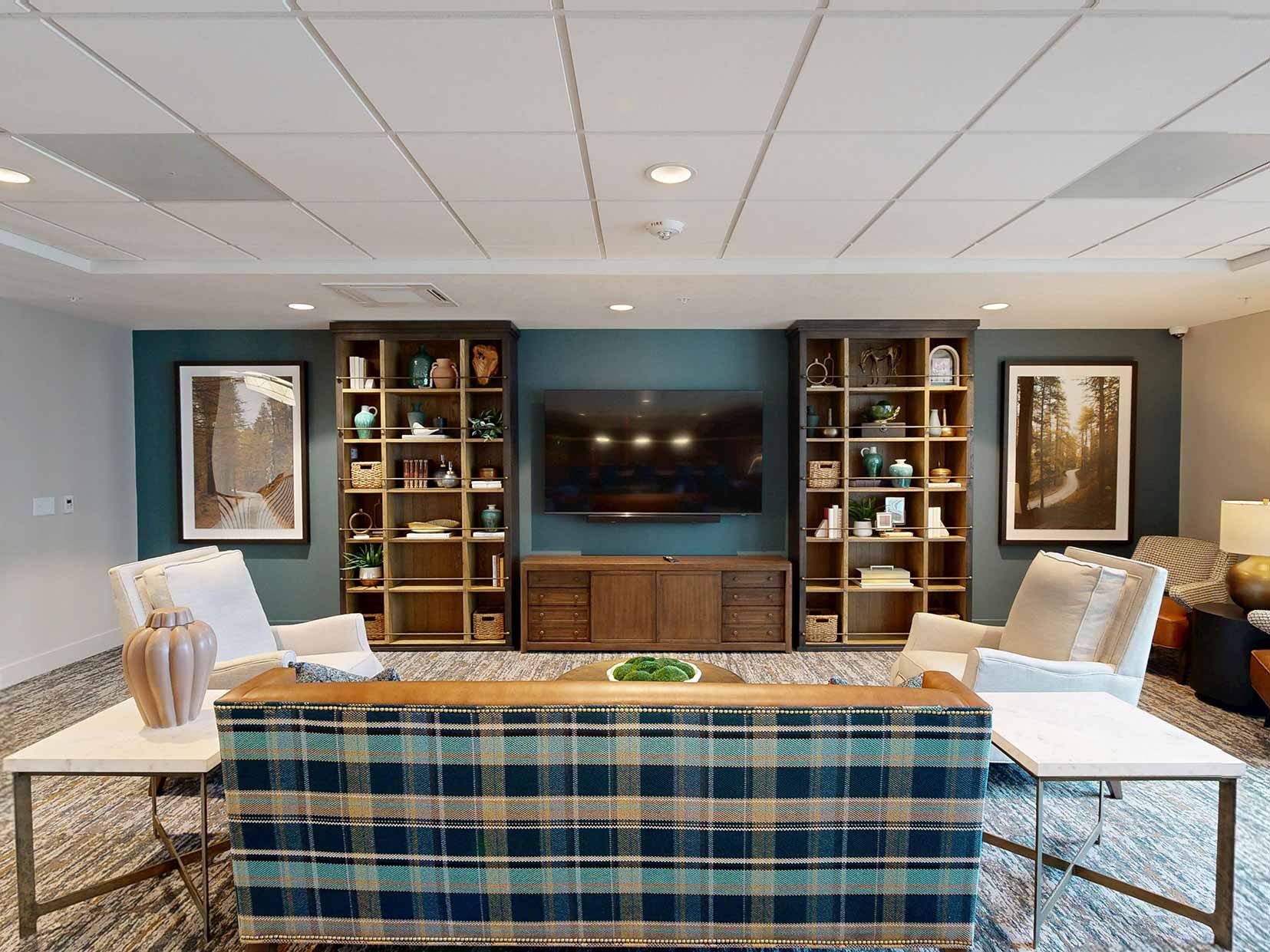 Cozy sitting area at Aura Independent Living, featuring elegant and inviting couches, chairs, shelves and television.